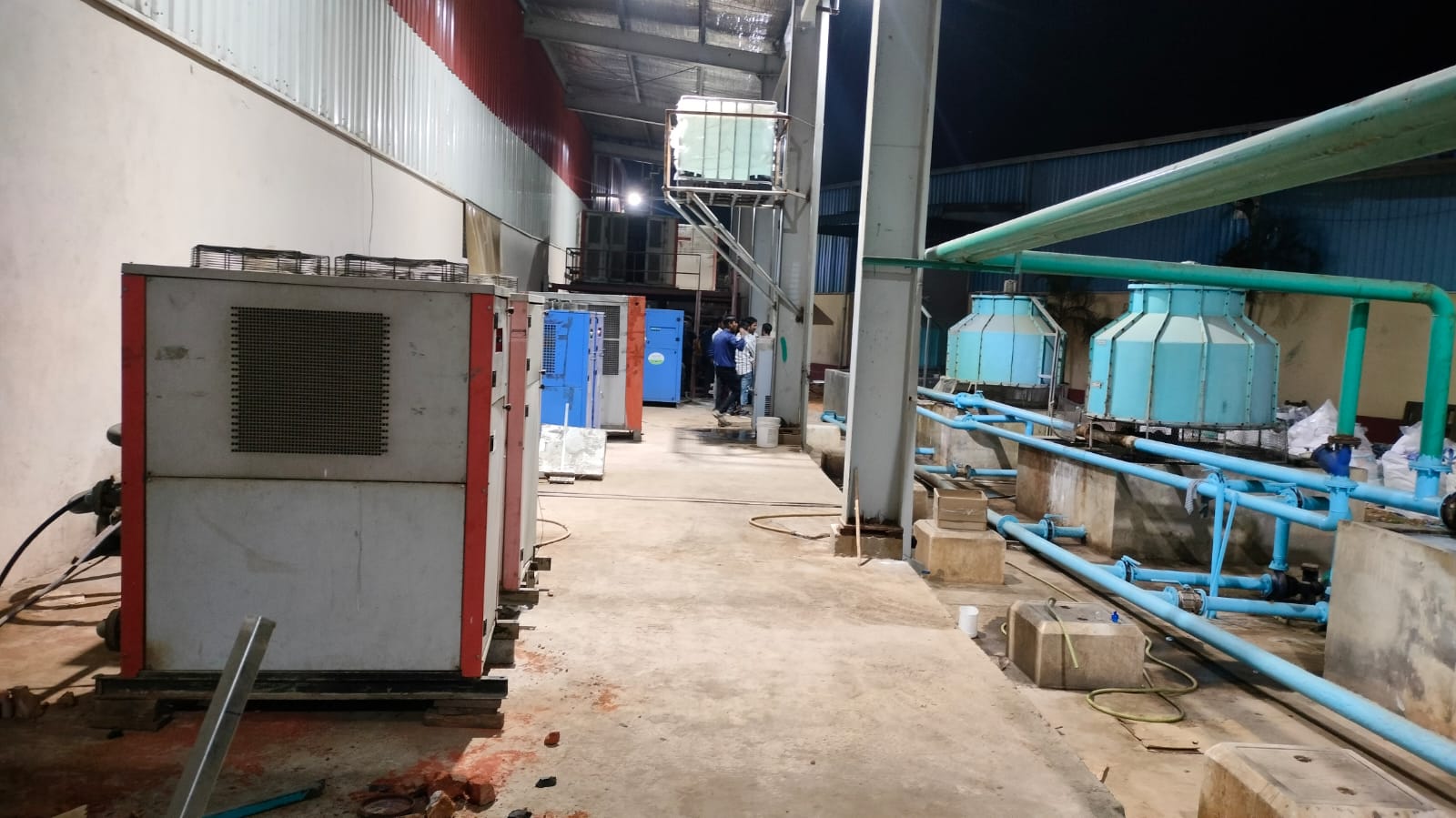 Air-cooled package chillers lined along the plant wall during a night-shift installation