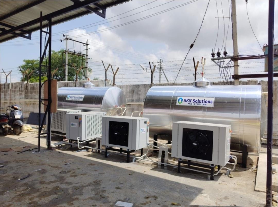 Two insulated hot water storage tanks with three air-source heat pump modules installed on steel stands